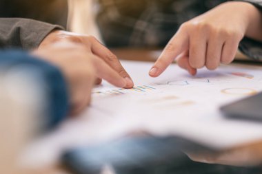 Bir grup işadamı, bir toplantıda iş konuşurken evrak işlerini işaret ediyor.