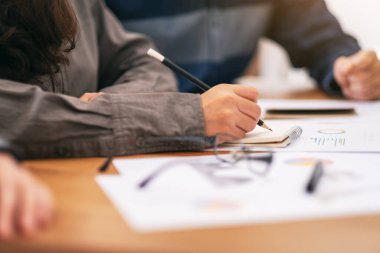 Bir iş kadını deftere yazı yazıyor ve iş bilgileri ve belgeler üzerinde çalışıyor.