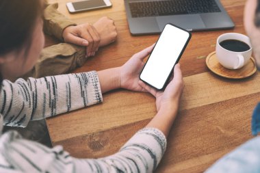 İnsanlar ahşap masada aynı model cep telefonunu kullanıyor ve ona bakıyorlar.