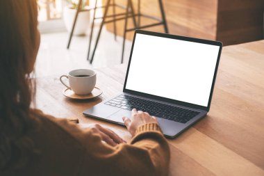 Laptop dokunmatik dokunmatik ekranlı, boş beyaz masaüstü ekranlı ve ahşap masada kahve fincanı olan bir kadının görüntüsü. 