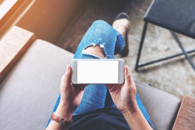 Kafede otururken elinde beyaz cep telefonu olan bir kadının en üst görünüm görüntüsü