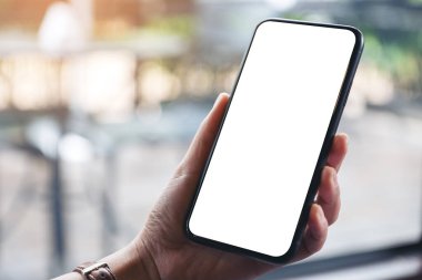 Siyah cep telefonunu boş masaüstü ekran ile tutan kadınların ellerinin görüntüsü