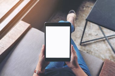 Kafede otururken elinde boş beyaz ekran olan siyah tabletli bir kadının üst görünüm görüntüsü