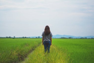 Ayakta duran ve güzel bir pirinç tarlasına bakan bir kadının rahat ve sakin görüntüsü.