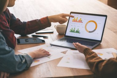 Üç iş adamı bir toplantıda çalışırken ve iş konuşurken dizüstü bilgisayar kullanıyor.