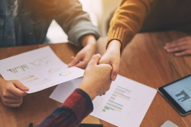 Toplantıda tokalaşan iki kişinin yakın çekim görüntüsü.