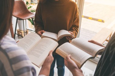 Çemberde dikilen ve birlikte kitap okumayı seven üç genç insan.