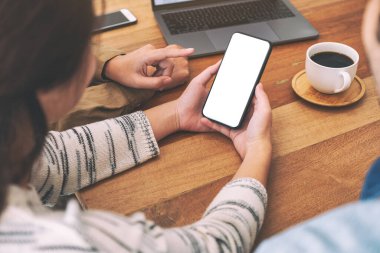 İnsanlar ahşap masada aynı model cep telefonunu kullanıyor ve ona bakıyorlar.