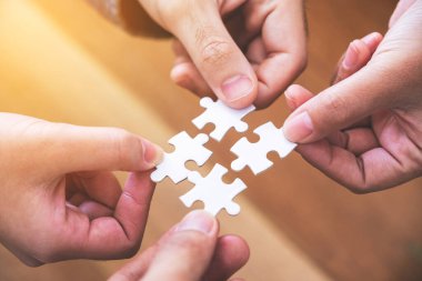 Birçok insanın el ele tutuştuğu ve bir parça beyaz yapbozu bir araya getirdiği yakın plan görüntüsü