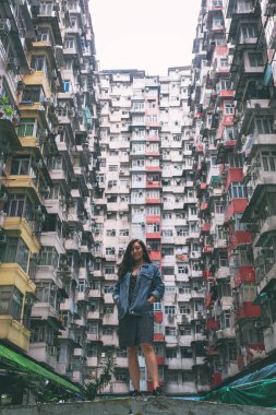 Quarry Bay, Hong Kong 'daki kalabalık yerleşim yerinin arasında duran güzel bir Asyalı kadın.