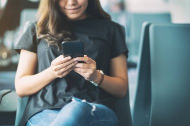 Havaalanında otururken cep telefonu kullanan bir kadın yolcu.