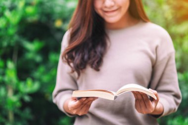 Parkta oturmuş kitap okuyan güzel bir Asyalı kadın. 