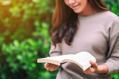 Parkta oturmuş kitap okuyan güzel bir Asyalı kadın. 