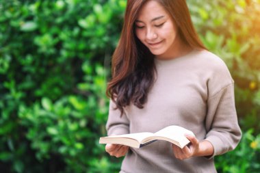 Parkta oturmuş kitap okuyan güzel bir Asyalı kadın. 