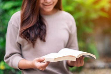 Parkta oturmuş kitap okuyan güzel bir Asyalı kadın. 