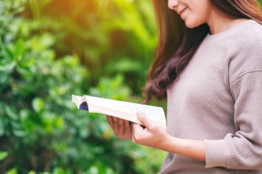 Parkta oturmuş kitap okuyan güzel bir Asyalı kadın. 