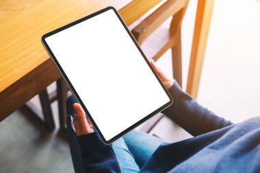Kafede otururken elinde siyah tablet olan beyaz ekranlı bir kadının görüntüsü.