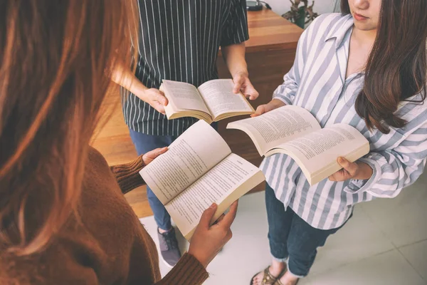 Çemberde dikilen ve birlikte kitap okumayı seven üç genç insan.