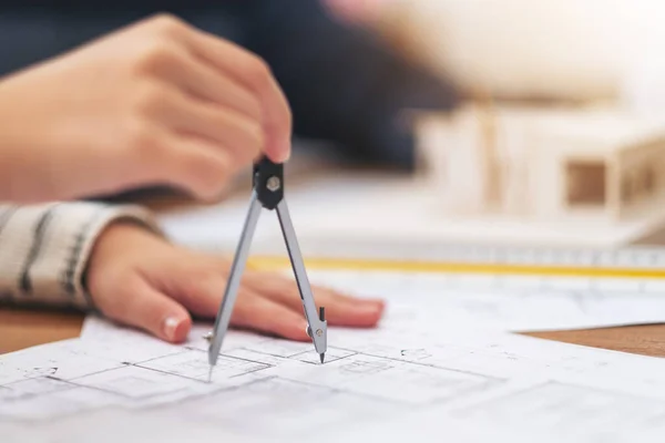 An architect using compass to draw and measure shop drawing in office