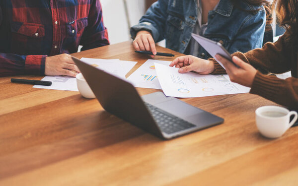 Three businessman using laptop and tablet pc while working and discussing business together in a meeting