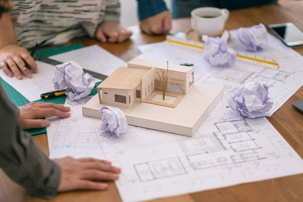 Group of an architect feel stressed after working on architecture model together with shop drawing paper on table in office