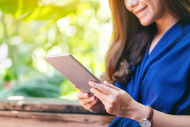 Bahçede otururken elinde tablet tablet kullanan bir kadının yakın plan görüntüsü