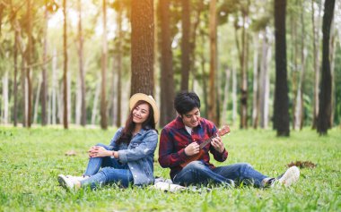 Genç bir çift ormanda ukulele oynuyor.