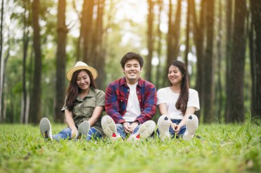 Parkta birlikte otururken ukulele oynayan bir grup genç.