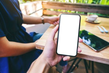 Kafe 'de kahve içen, elinde siyah cep telefonu olan beyaz ekranlı bir adamın görüntüsü.
