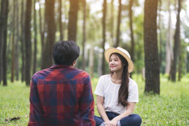 Parkta birlikte oturan Asyalı bir çift.