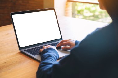 Laptop bilgisayar klavyesinde yazı yazan ve kullanan bir kadının resmi. Tahta masadaki boş beyaz masaüstü ekran. 