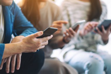 Birlikte otururken cep telefonu ve tablet bilgisayarı kullanan ve inceleyen bir grup insan