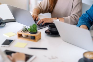 Ofisteki masadaki dizüstü bilgisayar ve tablet bilgisayar kullanan ve çalışan insanların yakın plan resmi