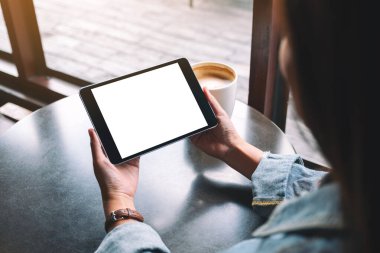 Siyah tabletli, beyaz ekranlı ve masada kahve fincanı olan bir kadının görüntüsü. 
