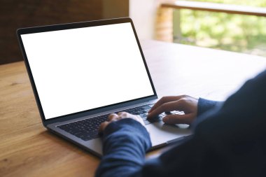 Laptop bilgisayar klavyesinde yazı yazan ve kullanan bir kadının resmi. Tahta masadaki boş beyaz masaüstü ekran. 