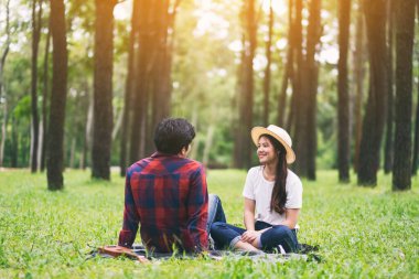 Parkta birlikte oturan Asyalı bir çift.