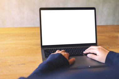 Laptop bilgisayar klavyesinde yazı yazan ve kullanan bir kadının resmi. Tahta masadaki boş beyaz masaüstü ekran. 