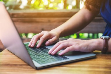 Masadaki dizüstü bilgisayarda çalışan ve yazan bir kadının yakın plan görüntüsü.