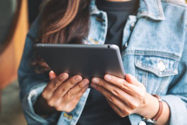 Kafede otururken elinde tablet bilgisayar kullanan bir kadının yakın plan görüntüsü