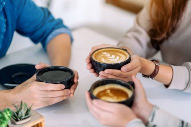 Kafe 'deki masada kahve içen insanların yakın çekim görüntüsü.