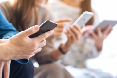 Birlikte otururken cep telefonu ve tablet bilgisayarı kullanan ve inceleyen bir grup insan