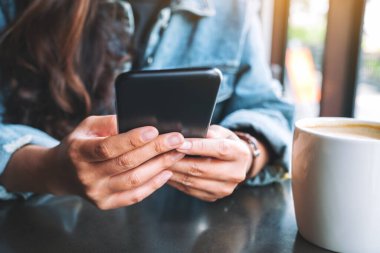 Elinde tutan, kullanan ve cep telefonuna bakan bir kadının yakın plan görüntüsü