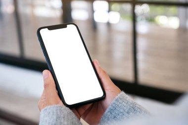 Boş masaüstü ekran ile siyah cep telefonu tutan bir kadının görüntüsü