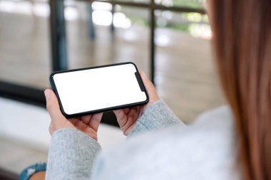 Boş masaüstü ekran ile siyah cep telefonu tutan bir kadının görüntüsü