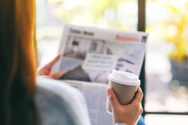 Sabahları gazete okuyan ve kahve içen bir kadının yakın plan görüntüsü.