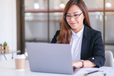 İş kadınının ofiste çalışırken dizüstü bilgisayar kullanıp daktilo kullandığı yakın plan resmi