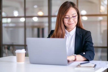 İş kadınının ofiste çalışırken dizüstü bilgisayar kullanıp daktilo kullandığı yakın plan resmi