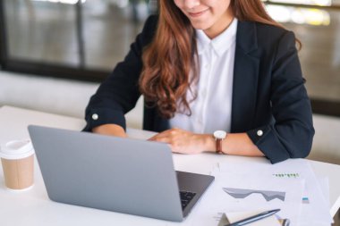 İş kadınının ofiste çalışırken dizüstü bilgisayar kullanıp daktilo kullandığı yakın plan resmi