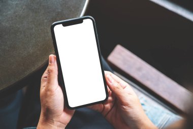 Boş beyaz masaüstü ekran ile siyah bir cep telefonu tutan bir kadının görüntüsü 