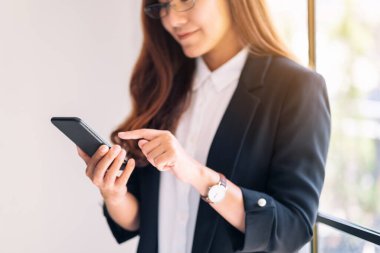 Cep telefonu tutan ve kullanan bir iş kadınının yakın plan görüntüsü